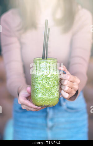 Frau hand Smoothie schütteln vor ihr. Das Trinken von einem gesunden grünen Smoothie Konzept. Stockfoto