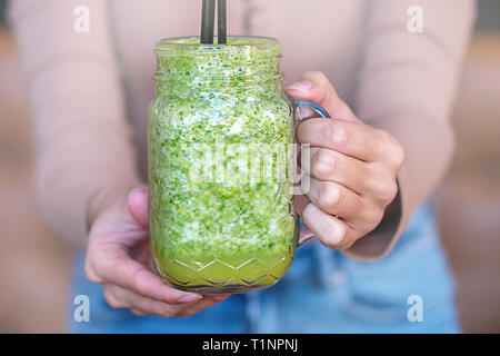Frau hand Smoothie schütteln vor ihr. Das Trinken von einem gesunden grünen Smoothie Konzept. Stockfoto