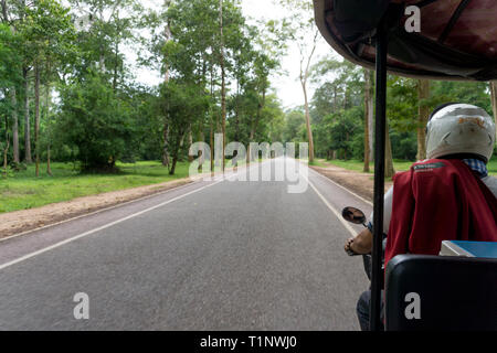 Tuk Tuk (remorque) Fahren auf eine leere Straße in der Tempelanlage Angkor Wat in der Nähe von Siem Reap, Kambodscha Stockfoto