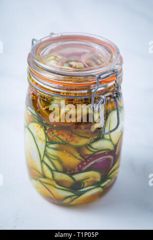 Nahaufnahme von einer würzigen Zucchini Zwiebel rot Essiggurke marinade in einem verschlossenen Marmeladenglas mit einem weißen Hintergrund. Eingelegtes Gemüse in einem jar. Stockfoto