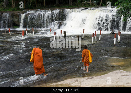 Zwei junge Mönche in orangefarbenen Gewändern ins Wasser mit einem Wasserfall im Hintergrund gekleidet Stockfoto