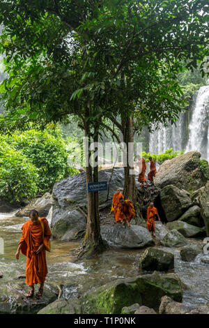 Kulen Mountain, Siem Reap, Kambodscha - 24. Juli 2018: Gruppe von buddhistischen Mönchen Überquerung des Flusses mit einem wunderschönen Wasserfall im Hintergrund Stockfoto