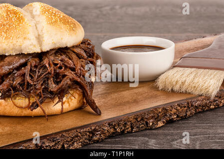 Nahaufnahme auf Schweinefleisch Sandwich und Barbecue Sauce auf Holzbrett gezogen. Stockfoto