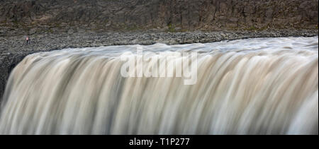Touristen stehen am Ufer des fallenden Wassers der mächtigsten Wasserfall Europas - Dettifoss, in Jokulsargljufur National Park, Island. Stockfoto