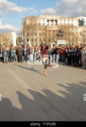 Große Menschenmenge genießt das street Entertainment Show von akrobaten auf dem Trafalgar Square, London, England, UK an einem sonnigen Nachmittag im März. Stockfoto