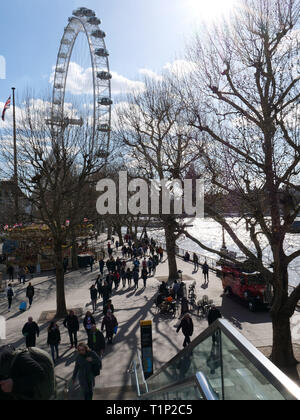 Touristen und Einheimische, die das Londoner Spaziergang entlang der Themse an der South Bank in der Nähe des London Eye und die warmen Sonnenstrahlen an einem Nachmittag Ende März genießen. Stockfoto