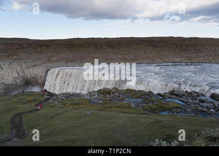 Touristische bewundernden Blick des fallenden Wassers der mächtigsten Wasserfall Europas - Dettifoss. Jokulsargljufur National Park, Island. Weiße Nächte anzeigen Stockfoto