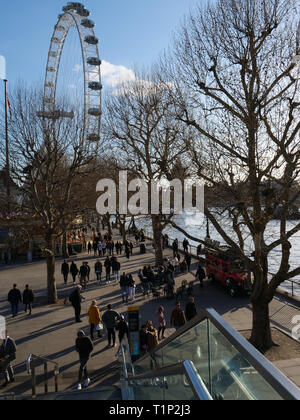 Touristen und Einheimische, die das Londoner Spaziergang entlang der Themse an der South Bank in der Nähe des London Eye und die warmen Sonnenstrahlen an einem Nachmittag Ende März genießen. Stockfoto