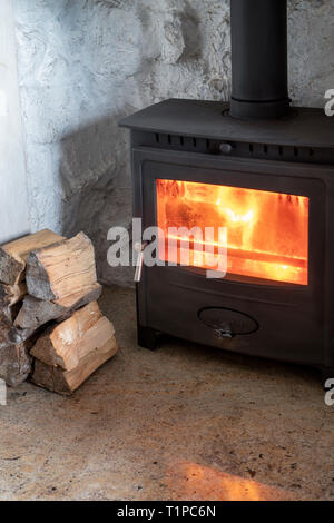 Holz Brennen in einem Kaminofen mit einem Stapel von Protokollen. Schottland Stockfoto