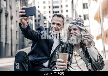 Lächelnd Geschäftsleute in dunklen Kostüm selfie mit glücklich heimatlos Stockfoto