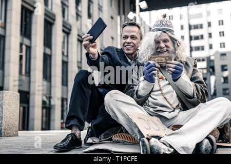 Vergeblich reichen Mann im Kostüm selfie der Spende Geld Stockfoto