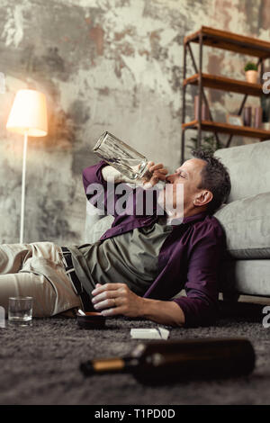 Alter Mann Wodka zu trinken direkt entschlossen von der Flasche Stockfoto