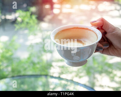 Frau hand mit einem weißen heißen Kaffee Tasse auf Natur Hintergrund mit kopieren. Stockfoto