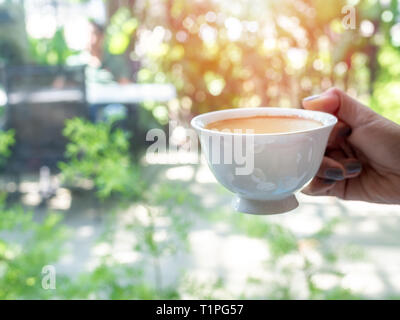 Frau hand mit einem weißen heißen Kaffee Tasse auf Natur Hintergrund mit kopieren. Stockfoto