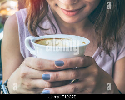 Close-up Frau Hände halten einen weißen heißen Kaffee Tasse und duftenden Kaffee im Cafe. Stockfoto