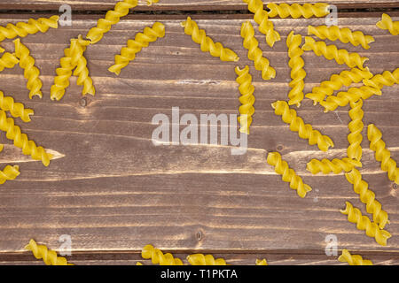 Viele Stücke von Raw italitan gelbe Nudeln torti flatlay auf braunem Holz Stockfoto