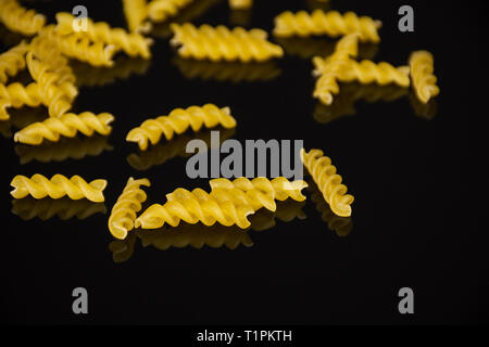 Viele Stücke von Raw italitan gelbe Nudeln torti auf schwarzem Glas Stockfoto