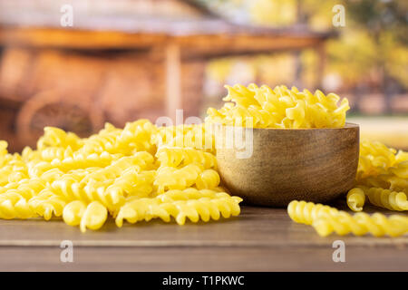 Viele Stücke von Raw italitan gelbe Nudeln torti mit Holzschale mit Karre im Hintergrund Stockfoto