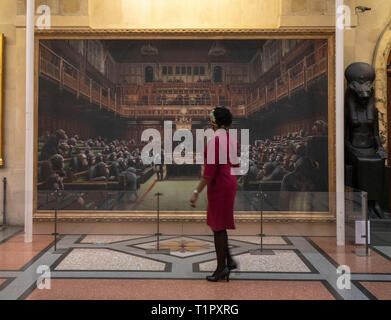 Ein Passant auf dem Gemälde "Das Parlament entwickelt" durch die Graffiti Künstler Banksy, der auf der Bristol Museum ist. Stockfoto