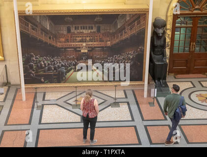 Die Passanten auf dem Gemälde 'Dentwickelte sich das Parlament durch die Graffiti Künstler Banksy, der auf der Bristol Museum ist. Stockfoto