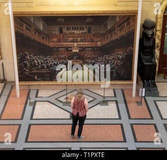 Ein Passant auf dem Gemälde "Das Parlament entwickelt" durch die Graffiti Künstler Banksy, der auf der Bristol Museum ist. Stockfoto