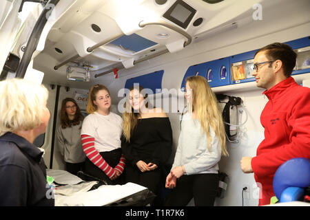 Rostock, Deutschland. 28. März, 2019. Am "Girls' Day" bei der Berufsfeuerwehr der Hansestadt, Schülerinnen sind das Innere eines Krankenwagens gezeigt, links Jana Bielefeldt, Sanitäter, rechts Sebastian Mund, Sanitäter. Mehr als 2000 Schülerinnen sind auf der diesjährigen "Girls' Day" in Unternehmen und Institutionen in Mecklenburg-Vorpommern erwartet, technische Berufe zu erkunden, unter anderem. Quelle: Bernd Wüstneck/dpa/Alamy leben Nachrichten Stockfoto