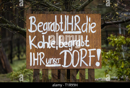 28. März 2019, Sachsen, Mühlrose: Blick in einen Vorgarten des Dorfes Mühlrose in der Lausitz, in dem ein Schild mit der Aufschrift 'Bury sie die Kohle, begraben Sie unser Dorf'. Mühlrose ist eines der letzten Dörfer in der Lausitzer Bezirk zu Weg zu braun Kohle, die am Anfang der 2030 s ausgebaggert werden. Lausitz Energie Bergbau AG rechnet mit einem Produktionsvolumen von 150 Millionen Tonnen Kohle. Die neue Mühle Rose liegt dann in der Schleife sieben Kilometer entfernt. Foto: Oliver Killig/dpa-Zentralbild/dpa Stockfoto