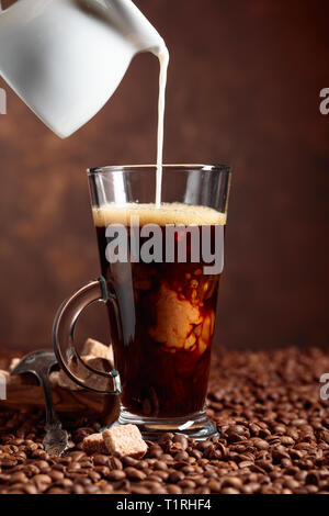 Kaffee Latte und braunen Zucker auf eine Tabelle mit Kaffeebohnen. Stockfoto
