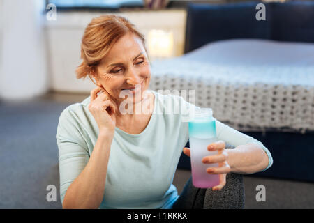 Angenehme reife Lady mit gebunden Haar ihr Kinn berühren Stockfoto