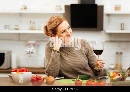 Angenehme Ingwer reife Frau Pullover tragen, während Sie in der Küche allein Stockfoto