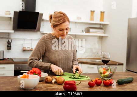 Konzentriert angenehme Dame in Gold Schmuck in Küche Stockfoto