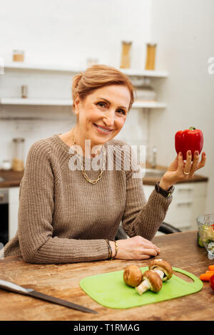 Freudige ansprechende erwachsenen Frau in beige Pullover und roten Pfeffer Stockfoto