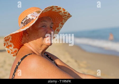 Großmutter auf Urlaub. Ältere Frau im Badeanzug am Meer. Alte Mann sitzt am Strand Stockfoto