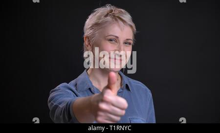 Closeup Portrait von Erwachsenen attraktive kaukasisch Weiblich fröhlich lächelnd und deutete mit dem Daumen nach oben, während bei Camera suchen Stockfoto