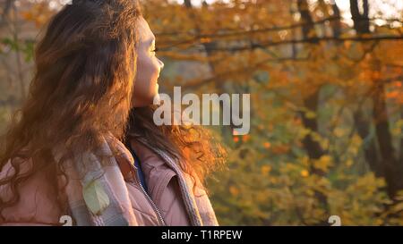 Hintere Porträt der Schönen lockigen Haaren kaukasische Mädchen drehte sie wieder von der Kamera, im herbstlichen Park. Stockfoto