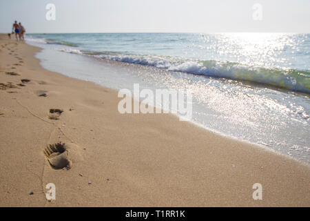 Abdrücke im Sand von Menschen zu Fuß entlang der Küste Stockfoto