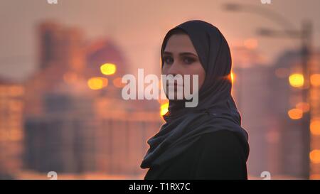 Closeup Portrait von jungen hübschen Frau im hijab drehen und Kamera mit glänzenden Gebäude auf dem Hintergrund Stockfoto