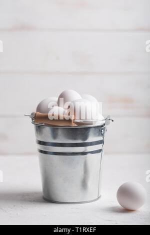 Weißes huhn eier im Eimer auf dem weißen Holz- Hintergrund. Vertikale Ausrichtung Stockfoto