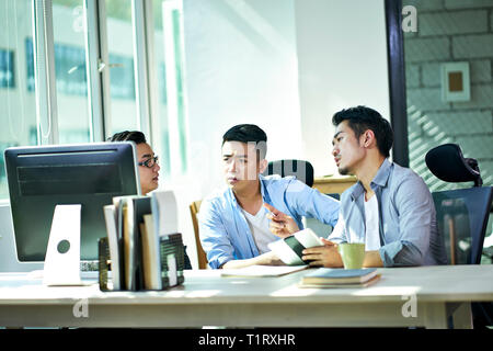 Drei jungen asiatischen Führungskräfte gemeinsam diskutieren business plan im Amt. Stockfoto