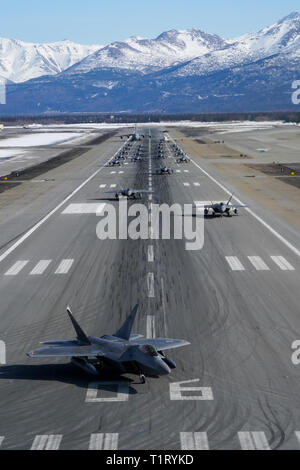 F-22 Raptors aus der 3 Flügel und 477th Fighter Group beteiligen sich in einer engen Formation Taxi mit einem E-3 Sentry und eine C-17 Globemaster III, bekannt als ein Elephant Walk, 26. März 2019, während eines Polar Kraft Übung in Joint Base Elmendorf-Richardson, Alaska. Dieser zweiwöchige Übung gibt staffeln die Möglichkeit, ihre Fähigkeiten unter Beweis zu stellen, Bereitstellen und liefern überwältigende bekämpfen Airpower. (U.S. Air Force Foto von Justin Connaher) Stockfoto