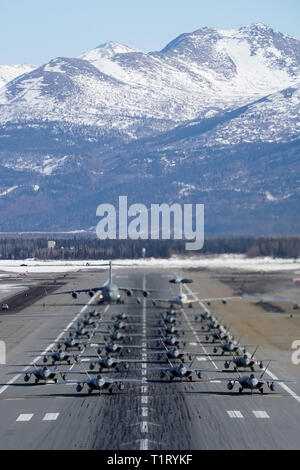 F-22 Raptors aus der 3 Flügel und 477th Fighter Group beteiligen sich in einer engen Formation Taxi mit einem E-3 Sentry und eine C-17 Globemaster III, bekannt als ein Elephant Walk, 26. März 2019, während eines Polar Kraft Übung in Joint Base Elmendorf-Richardson, Alaska. Dieser zweiwöchige Übung gibt staffeln die Möglichkeit, ihre Fähigkeiten unter Beweis zu stellen, Bereitstellen und liefern überwältigende bekämpfen Airpower. (U.S. Air Force Foto von Justin Connaher) Stockfoto