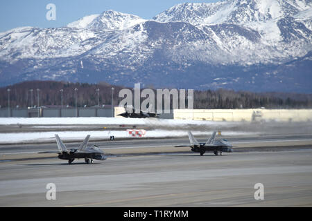 F-22 Raptors aus der 3 Flügel und 477th Fighter Group beteiligen sich in einer engen Formation Taxi, bekannt als ein Elephant Walk, 26. März 2019, während eines Polar Kraft Übung in Joint Base Elmendorf-Richardson, Alaska. Dieser zweiwöchige Übung gibt staffeln die Möglichkeit, ihre Fähigkeiten unter Beweis zu stellen, Bereitstellung und überwältigende Combat Power liefern. (U.S. Air Force Foto von Sheila deVera) Stockfoto