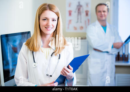 Portrait freundlicher, selbstbewusster Ärzte im Krankenhaus. Begeistertes medizinisches Personal bei der Arbeit. Weibliche Ärztin mit Stethoskop, die auf die Kamera blickt. Stockfoto