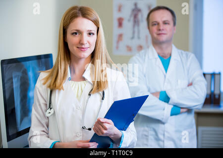 Portrait freundlicher, selbstbewusster Ärzte im Krankenhaus. Begeistertes medizinisches Personal bei der Arbeit. Weibliche Ärztin mit Stethoskop, die auf die Kamera blickt. Stockfoto