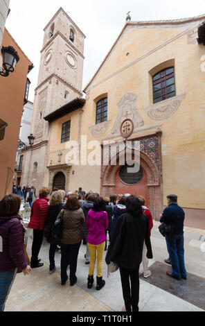 Malaga Tourismus - Touristen auf eine geführte Tour mit Blick auf die Iglesia de Santiago, die älteste Kirche in Malaga, Málaga, Andalusien, Spanien Stockfoto