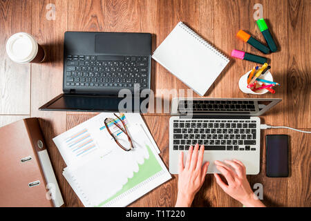 Zwei Personen im Büro Schreibtisch arbeiten, schreiben und mit Laptop, Ansicht von oben, flach. Smart Watch an Hand und Smart Phone auf dem Tisch. Kaffeetasse Stockfoto