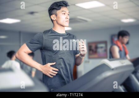 Asiatische junge Mann in Sportkleidung auf Laufband im Fitnessstudio | gesunde Aktivität Sport läuft Stockfoto