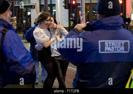 Ein Mitglied der der Derby Straße Pastor Team ist als Fotograf für zwei junge Frauen beschäftigt, während die Mannschaft auf Patrouille in Derby waren. Straße Pastor war Vorreiter in London im Januar 2003 und Derby Street Hirten ist eine Partnerschaft von 25 lokalen Kirchen, Gemeinden, Polizei, Lokalen und in verschiedenen Gruppen mit City Centre Street Business und Sicherheit. Jede Straße Pastor Teammitglied arbeitet mindestens eine Nacht im Monat, in der Regel von 10 Uhr bis um 4 Uhr. Stockfoto