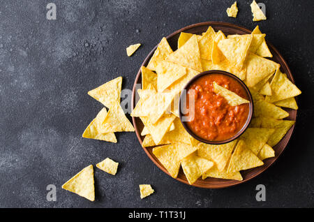 Nachos mais Chips mit pikanter Tomatensauce. Mexikanisches Essen Konzept. Gelber Mais totopos Chips mit Salsa Soße. Ansicht von oben. Stockfoto