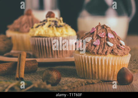 Hausgemachte Muffins Cupcakes mit Schokolade und Vanille Creme und Haselnüsse auf einem Holzbrett - Bild Stockfoto